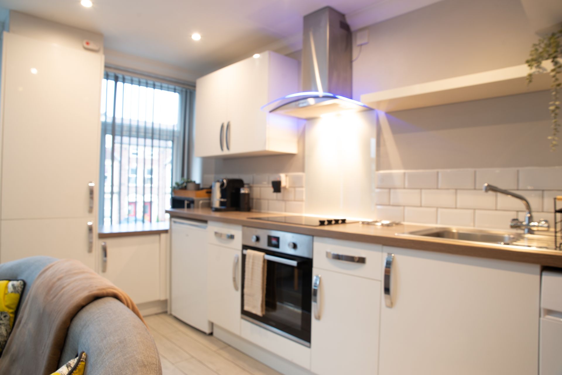 Modern white kitchen with stainless steel appliances, wood countertops, and a windowed dining nook