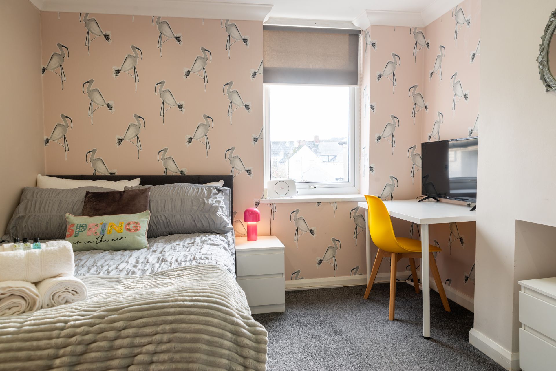 Cozy pink bedroom with bed, window, desk, and yellow chair