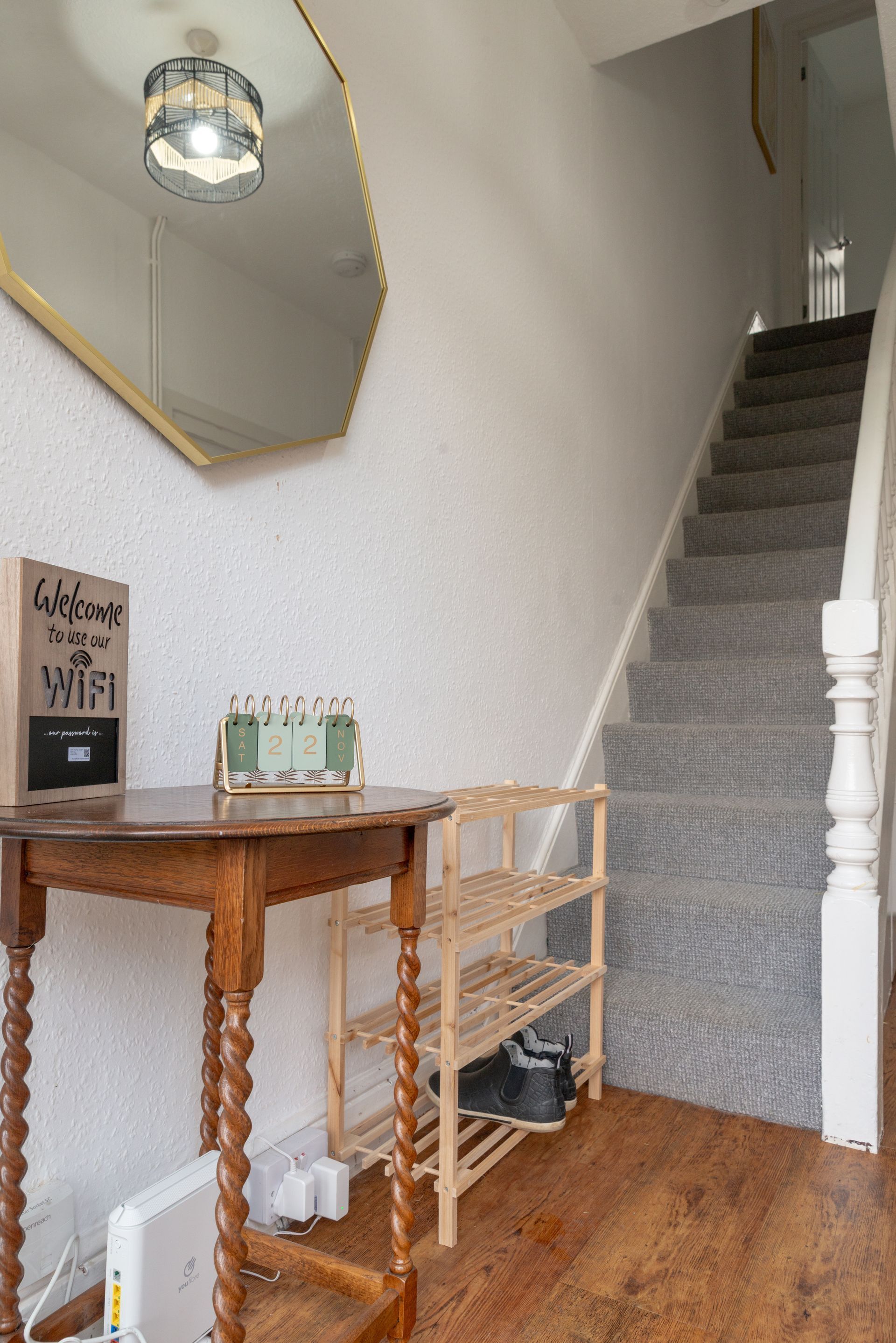 Entryway with stairs, wooden table, mirror, and carpeted staircase in a narrow hallway.
