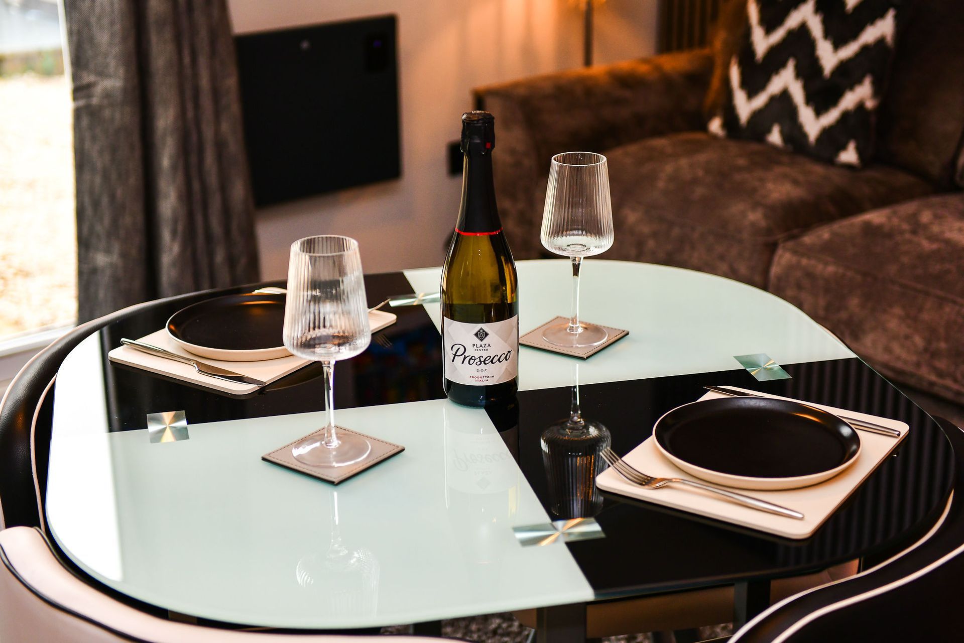 Modern dining table set with wine bottle, glasses, and plates in a cozy living room