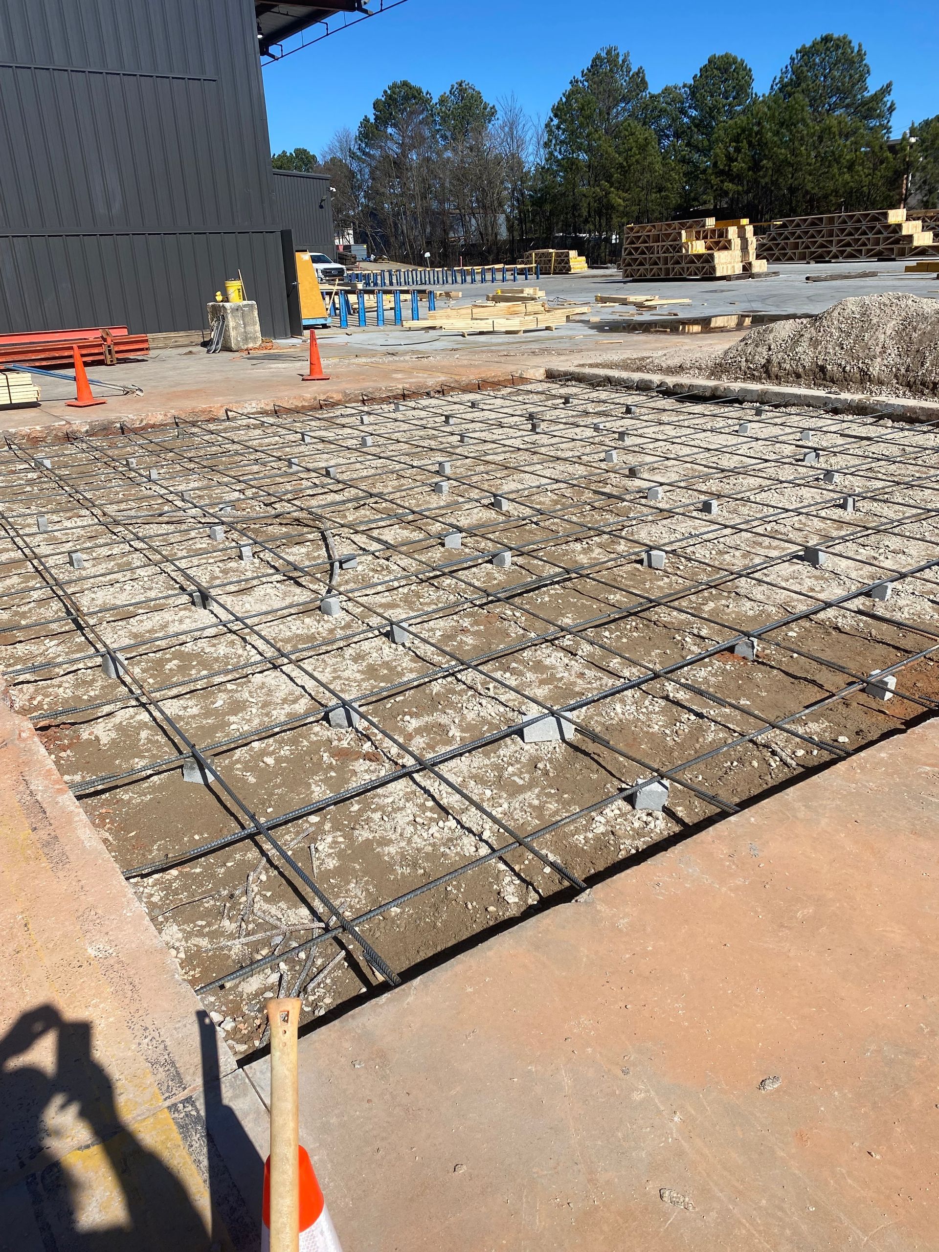 Construction site: Concrete foundation with rebar grid laid in preparation for pouring.