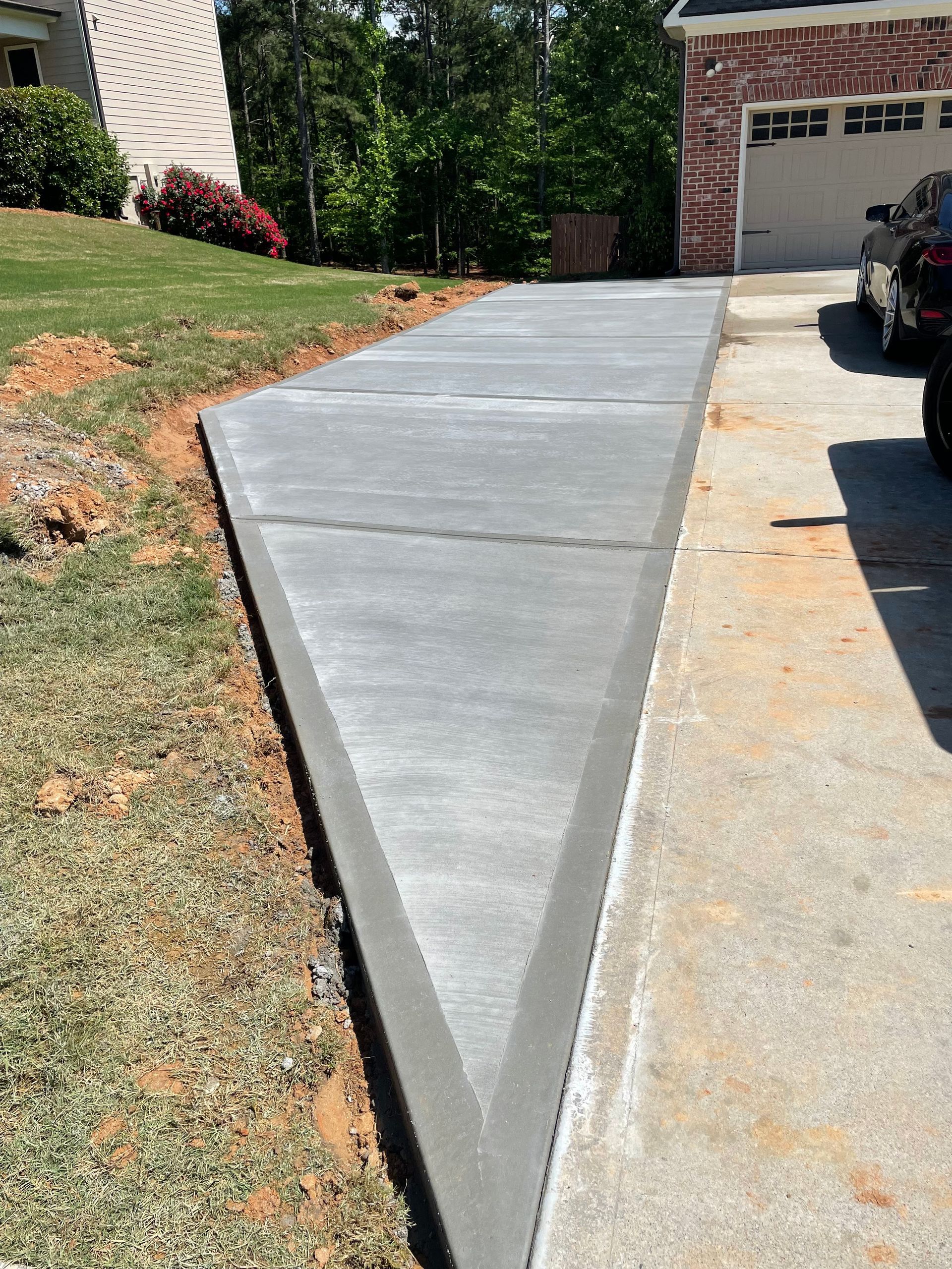 Newly poured concrete driveway leading to a house with a garage.