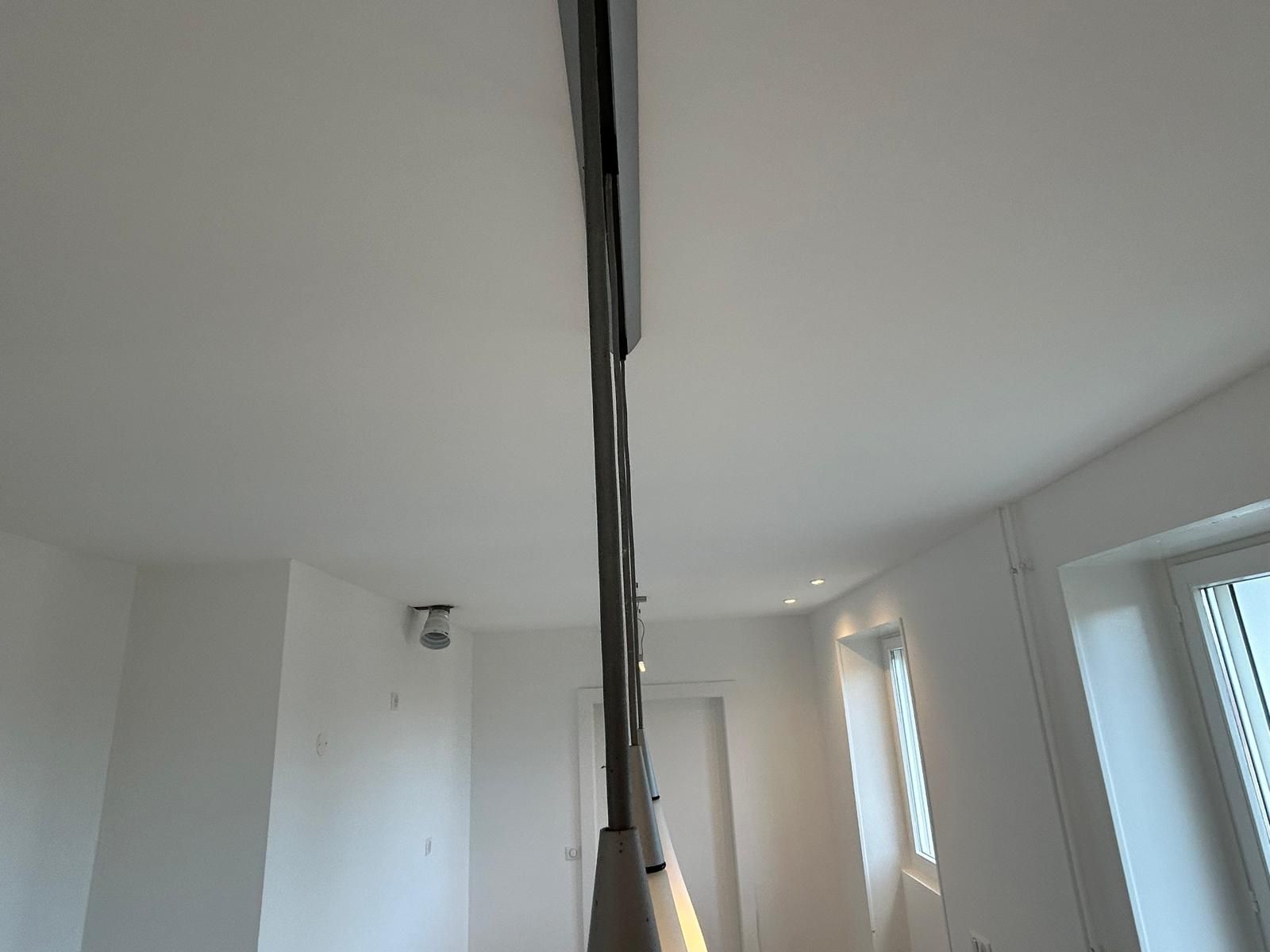 Pièce blanche lumineuse avec de grandes fenêtres et un luminaire suspendu central