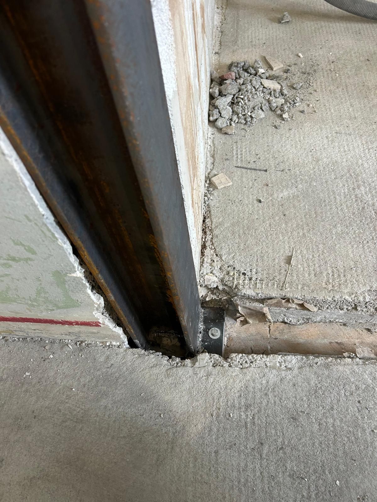 Cadre de porte en métal rouillé à la jonction d'un sol et d'un mur en béton fissuré
