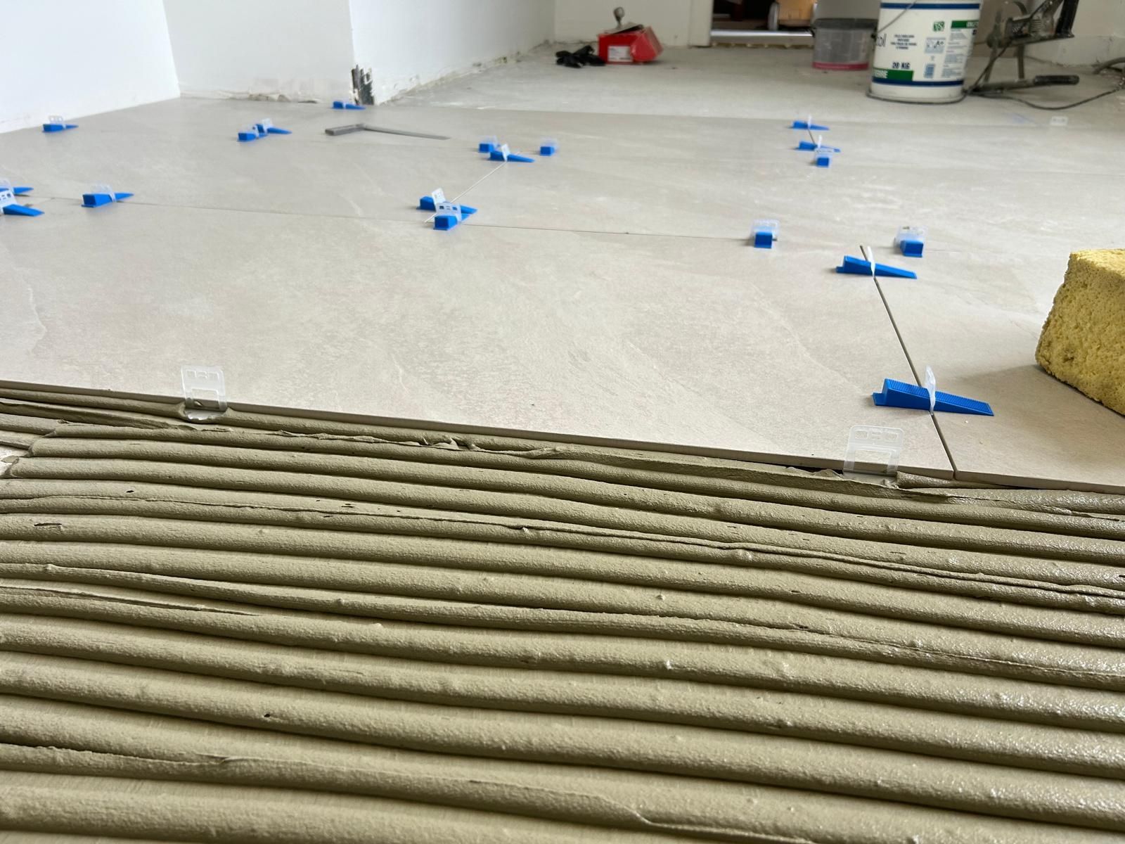 Pièce en rénovation avec des croisillons de carrelage bleus et une planche de bois au premier plan