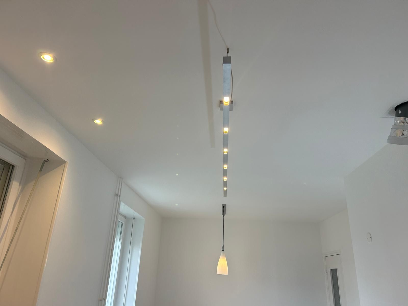 Couloir blanc moderne avec spots encastrés au plafond et lampe suspendue