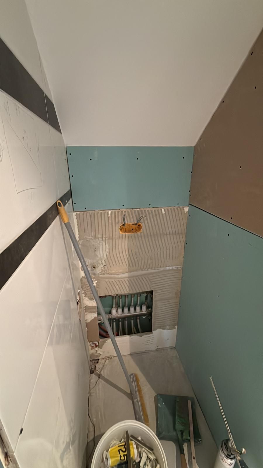 Cage d'escalier aux murs inachevés, avec une échelle et des outils de construction sur les marches.