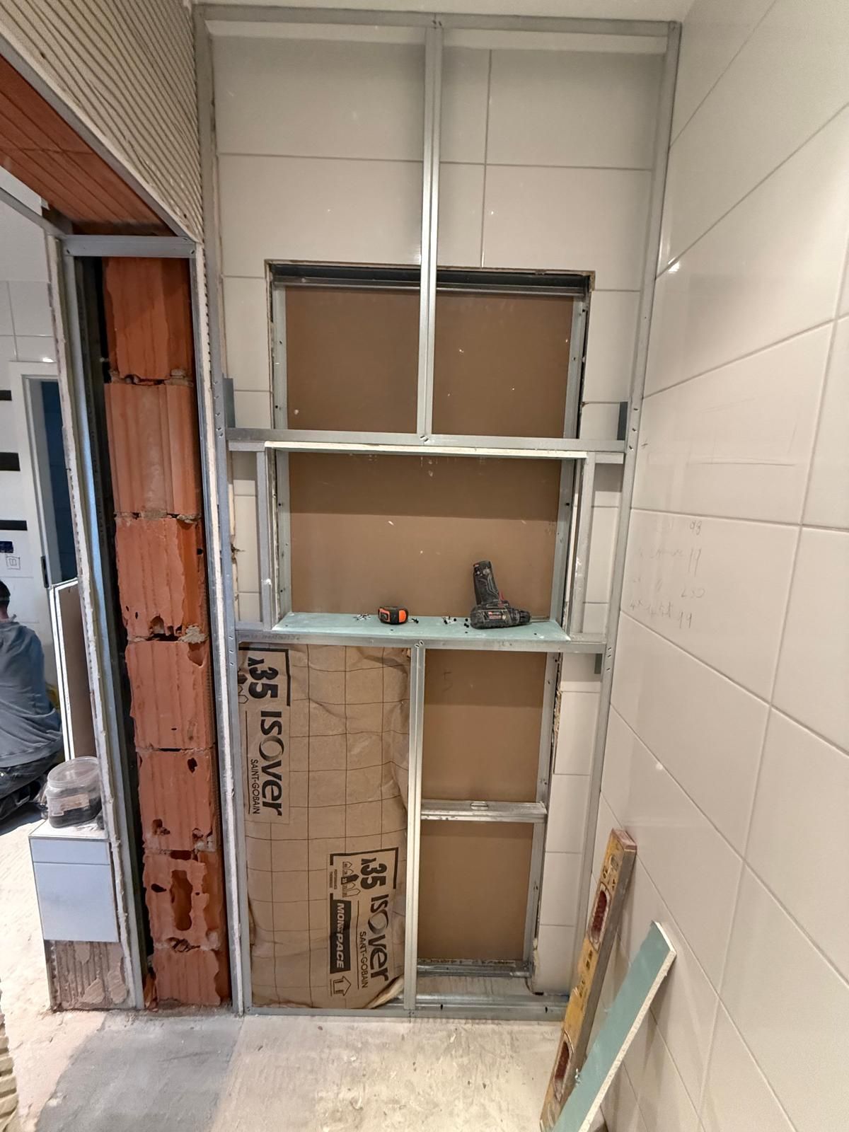 Pièce étroite carrelée avec une étagère murale intégrée et un encadrement de porte apparent en construction