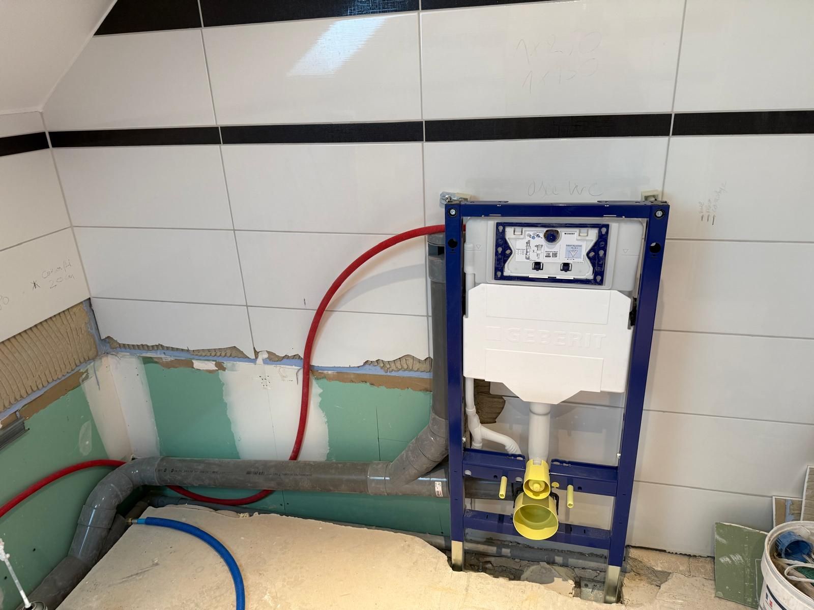 Mur de salle de bain avec tuyauterie apparente et cadre de réservoir de toilette bleu en construction