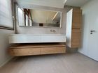Une salle de bain avec un lavabo, un miroir et des armoires.