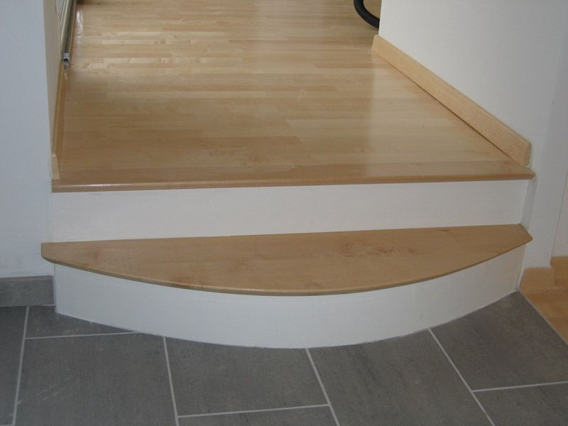 Escalier en bois avec bord avant courbé, contremarches blanches et plancher de bois franc.