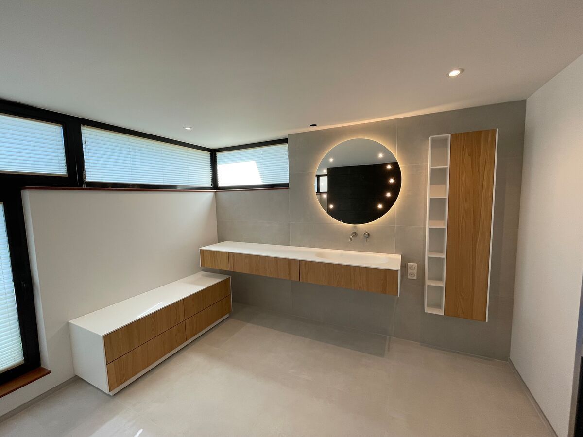 Une salle de bain avec un lavabo, un miroir et des armoires.