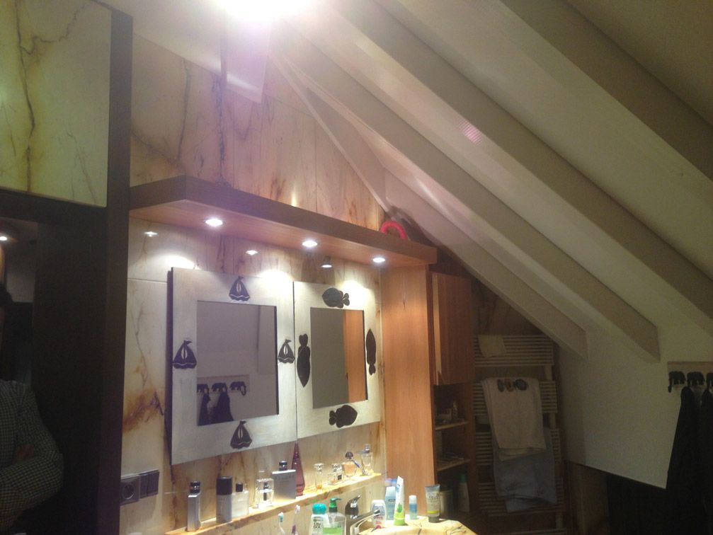 Une salle de bain avec un plafond incliné et deux miroirs