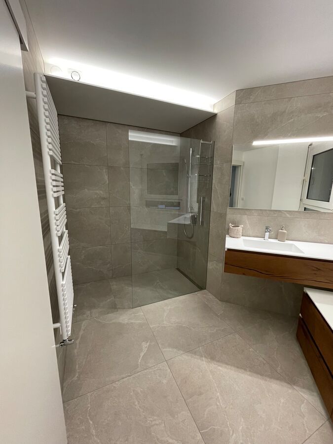 Une salle de bain avec douche à l'italienne, lavabo et miroir.