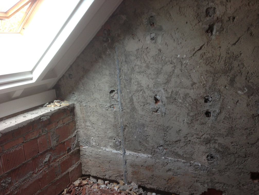 Un mur de briques à côté d'une fenêtre dans une pièce avec un mur en béton.
