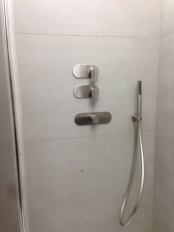 Une douche avec trois robinets et une pomme de douche.