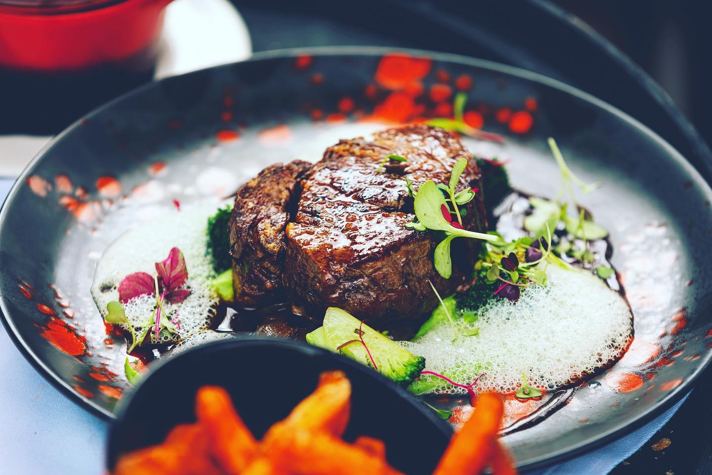 A black plate with a steak and french fries on it
