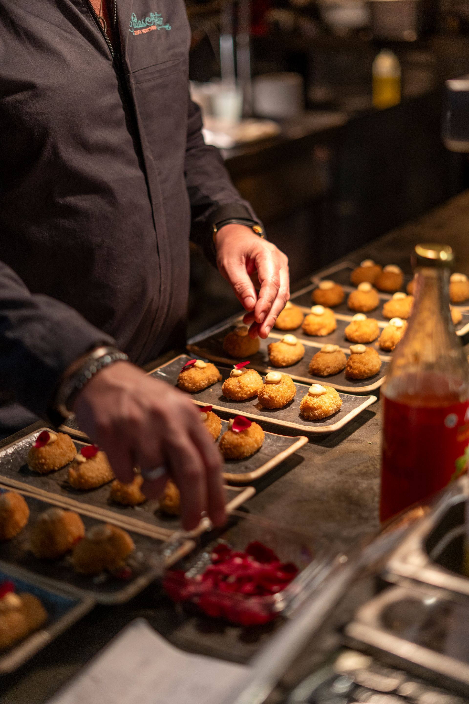A man is preparing food in a kitchen with a bottle of ketchup in the background