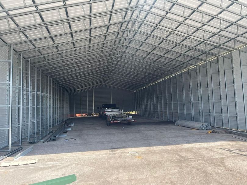 Large empty metal warehouse interior with a few vehicles and construction materials inside