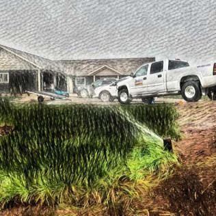 A white pickup truck parked in front of a rural house as a sprinkler sprays water over a foreground of tall green grass.