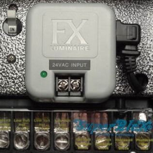 A grey FX Luminaire controller module mounted on a textured surface above a terminal block with wired connections.