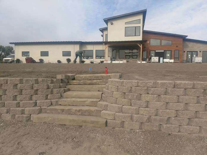 Newly constructed home with stone retaining walls and steps leading up to the entrance.