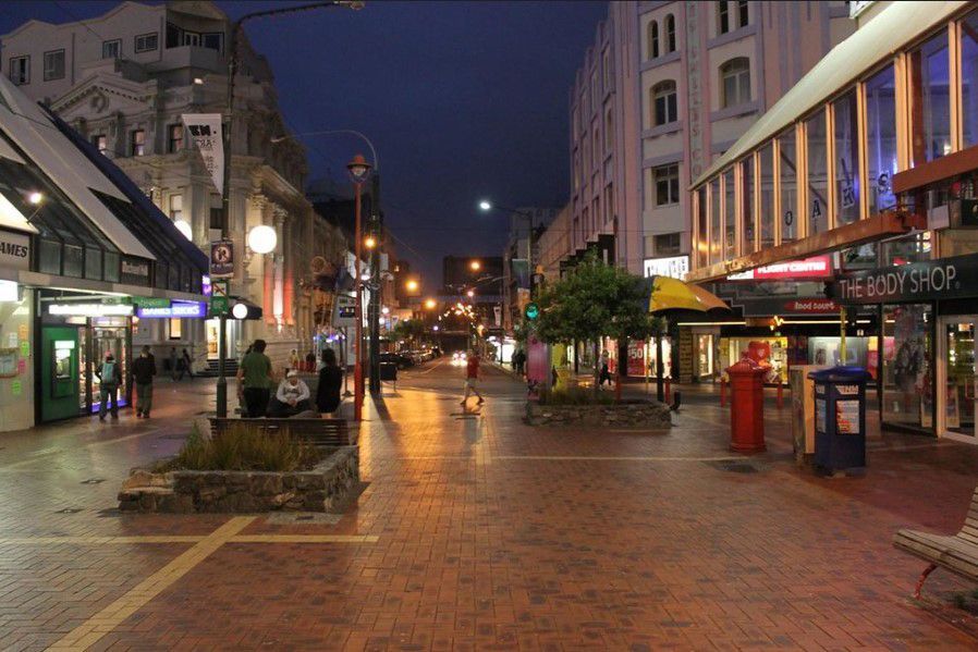 A city street at night with a telephone booth in the middle