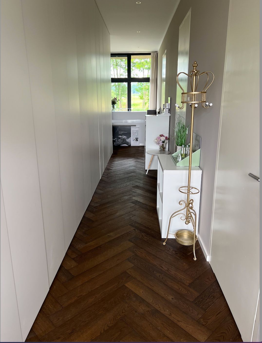 Ein langer Flur mit Holzboden und weißen Wänden