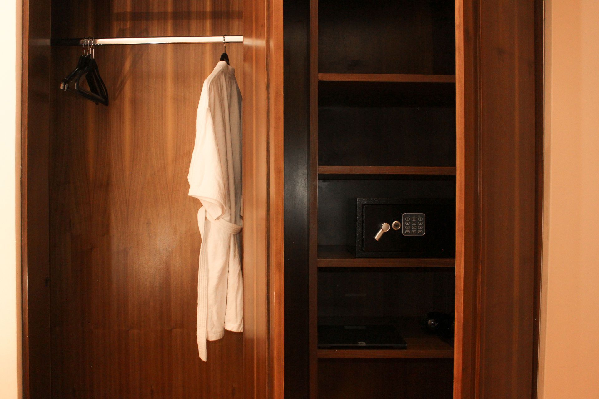Armario de madera abierto con una camisa blanca colgada y estantes a la derecha.