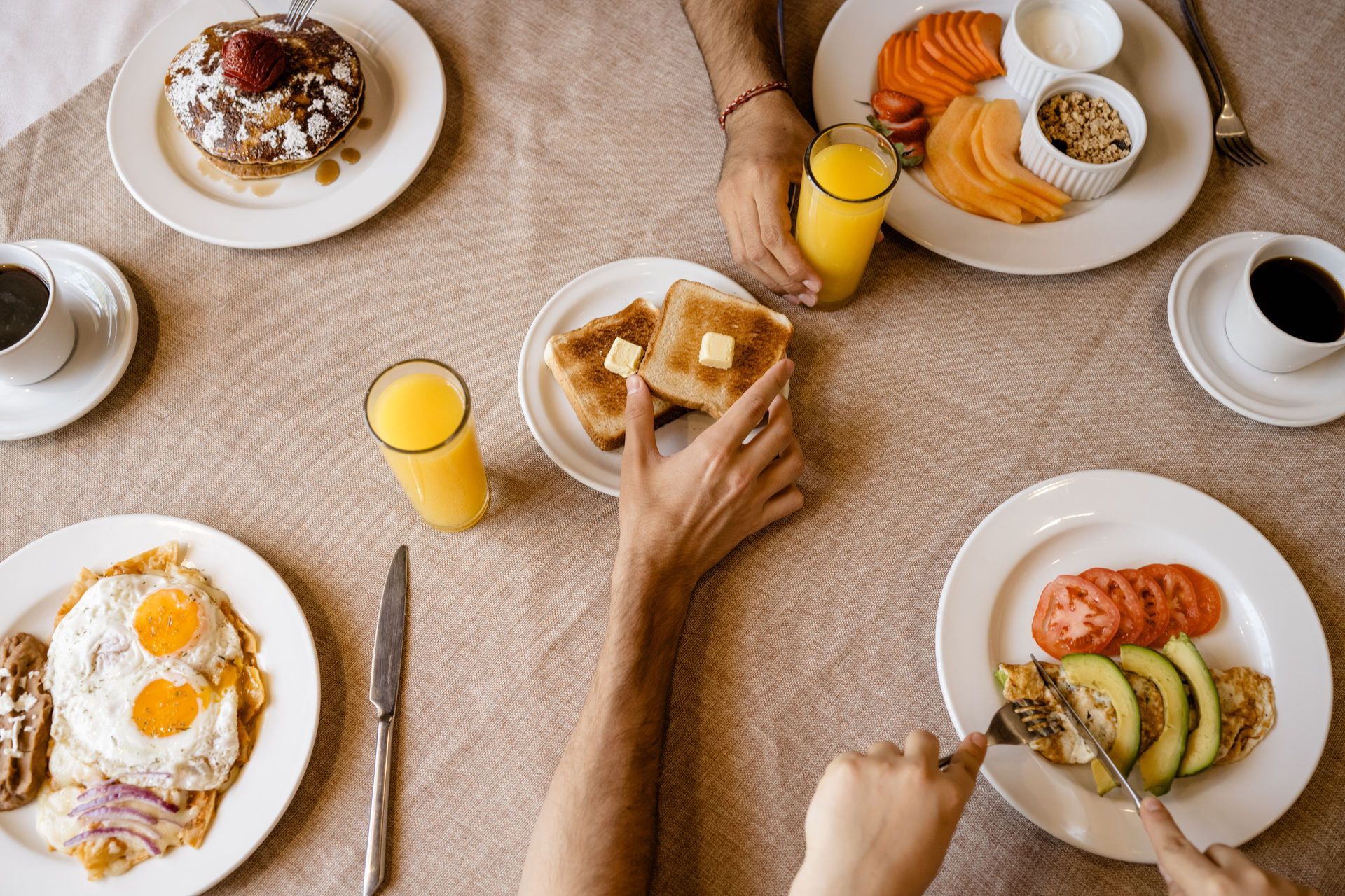 Mesa de desayuno con panqueques, huevos, tostadas de salmón, fruta, café y jugo de naranja.