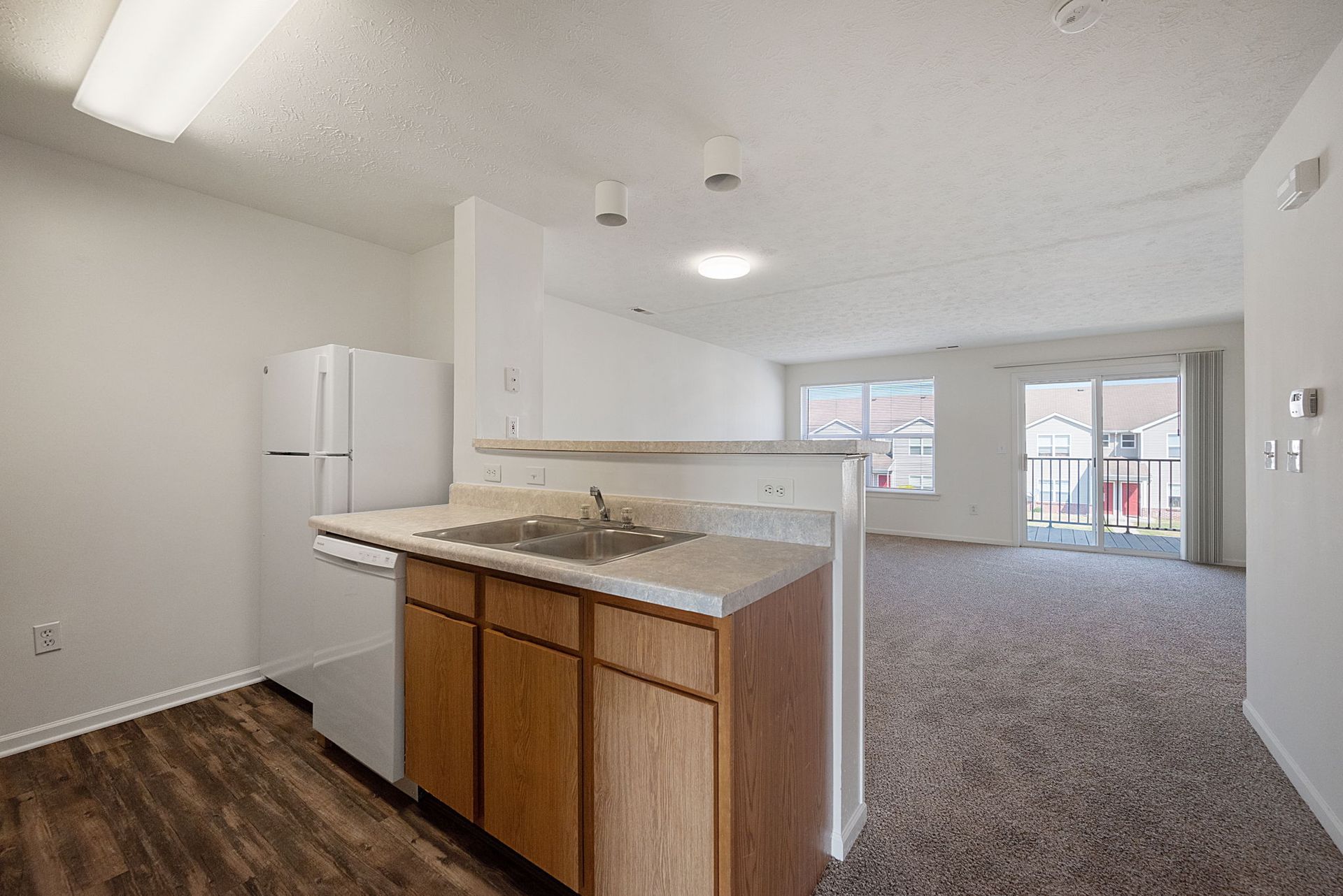 A kitchen with a sink , refrigerator , dishwasher and sliding glass doors.