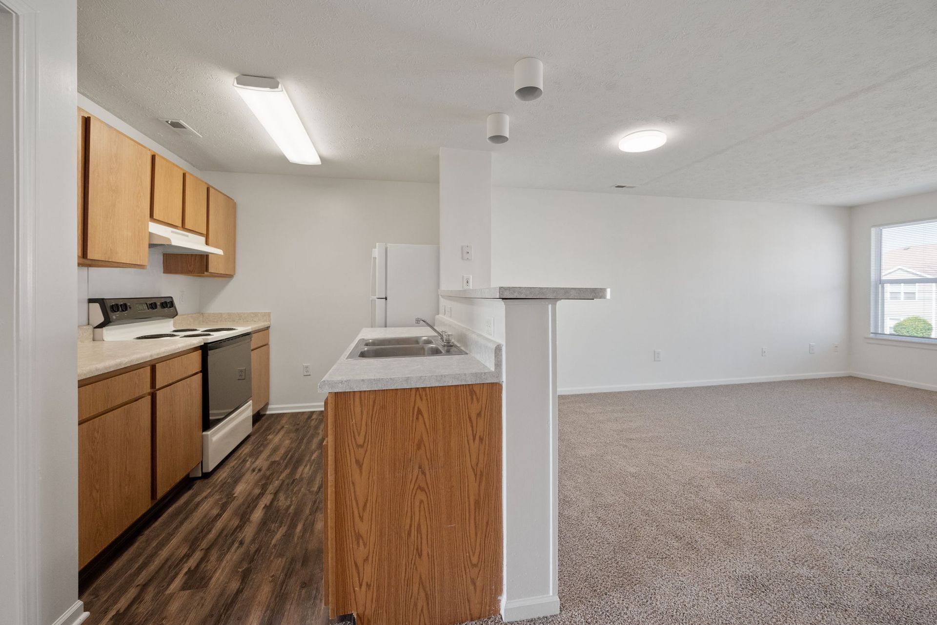 A kitchen with wooden cabinets , stainless steel appliances , and a refrigerator.