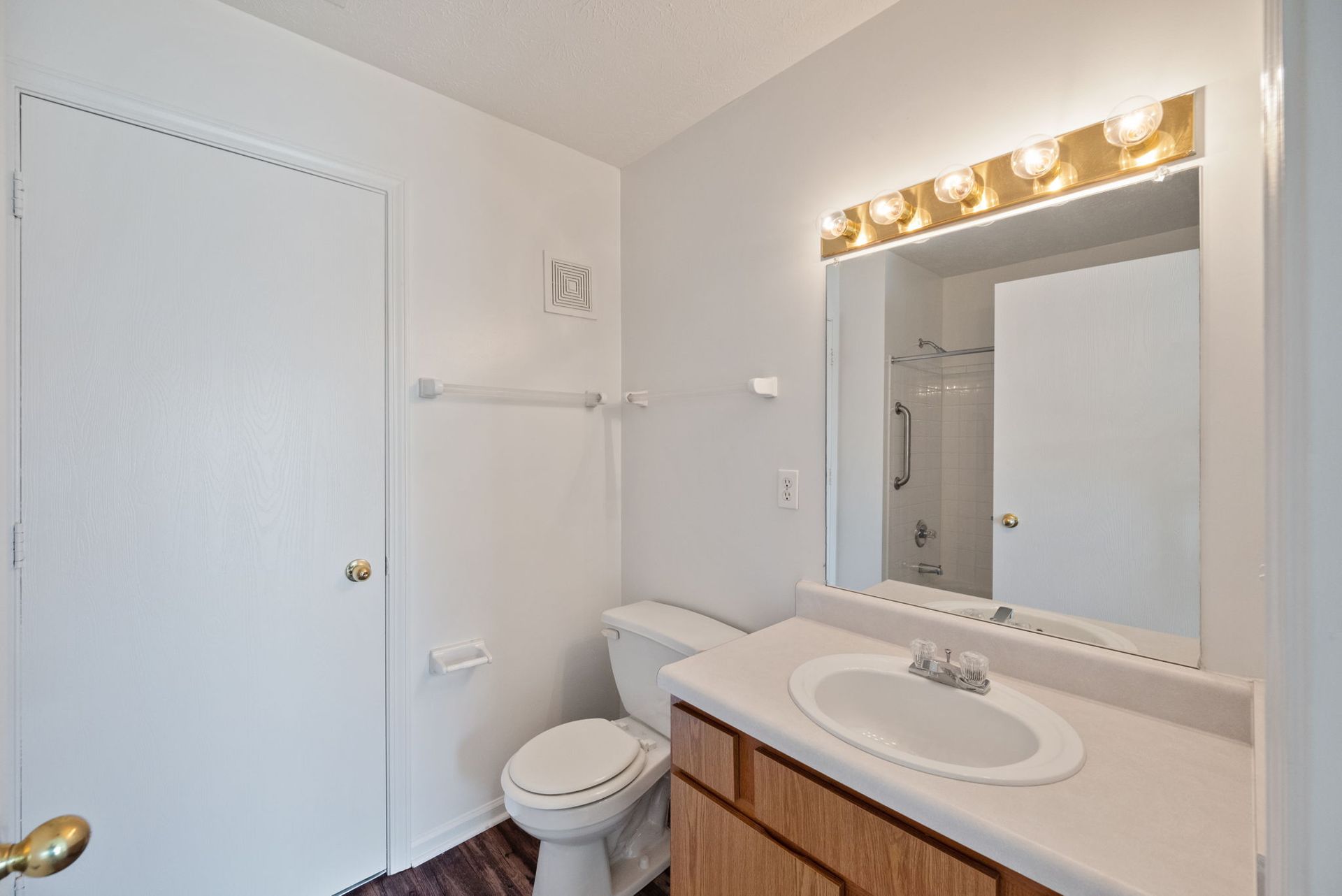 A bathroom with a toilet , sink and mirror.