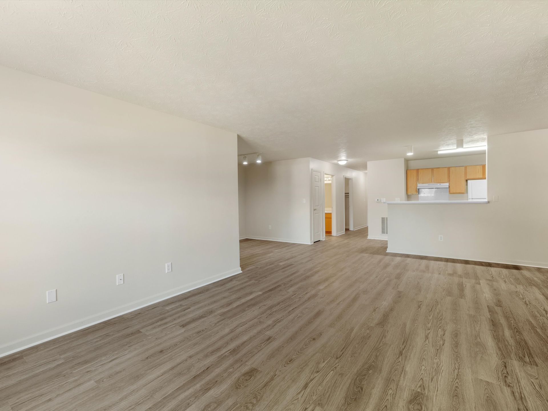 An empty living room with hardwood floors and white walls.