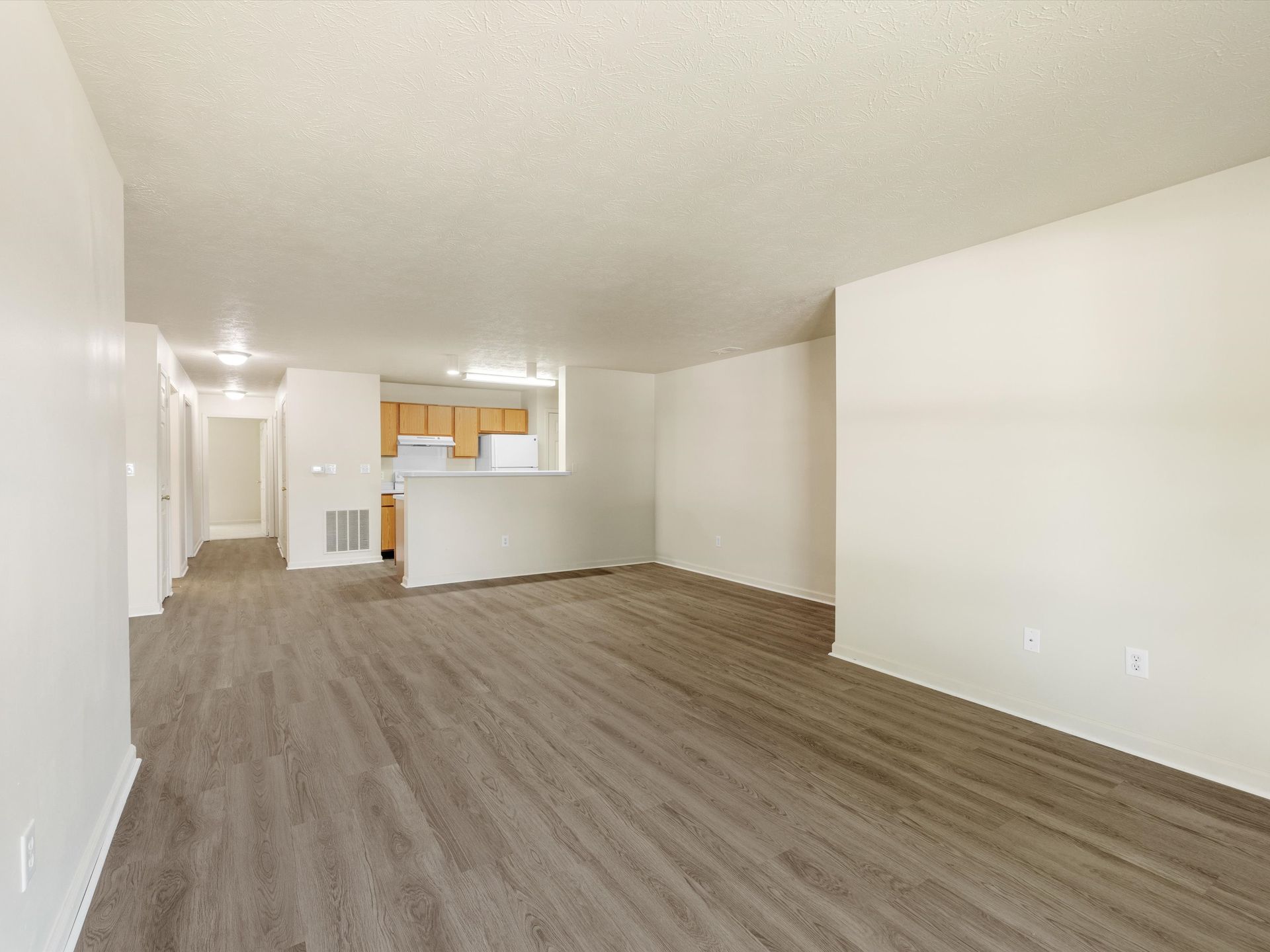An empty living room with hardwood floors and white walls.