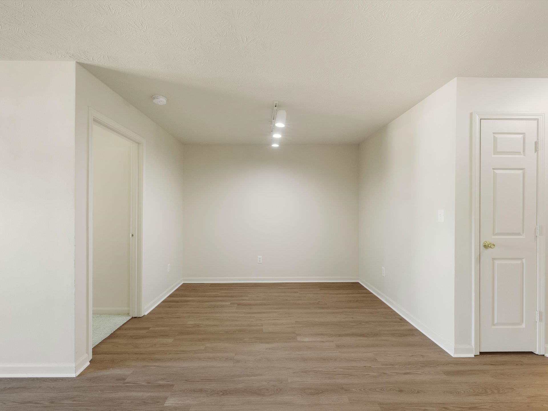 An empty room with hardwood floors and white walls.