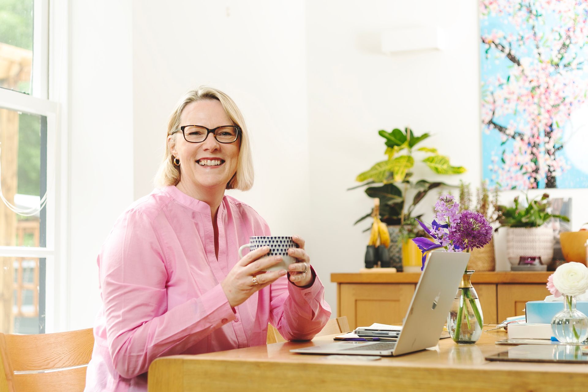 Relaxed portrait of a woman sat at a table with a coffee shot by Dammo Photography