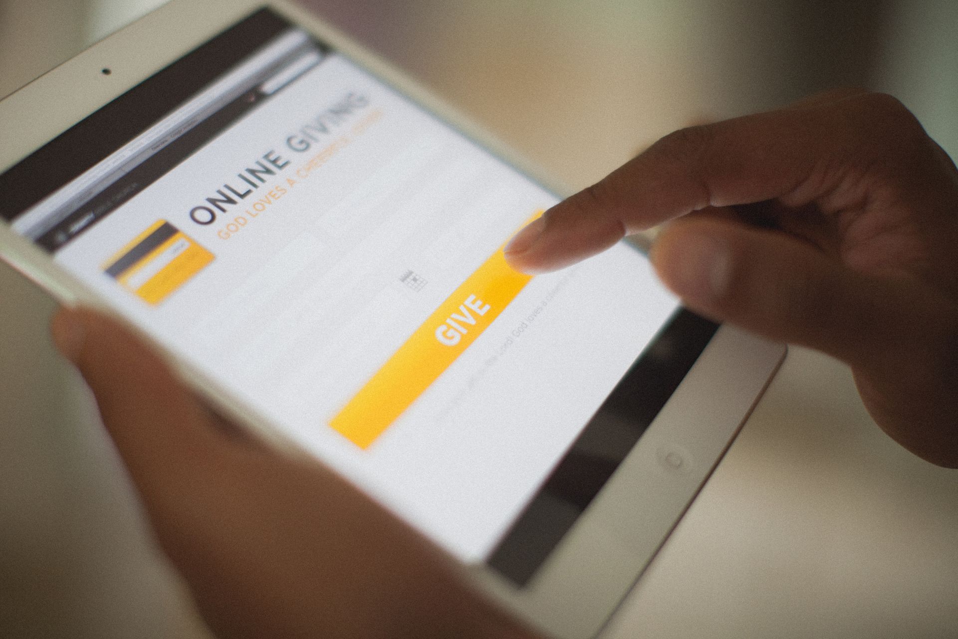 Hands tapping an online payment screen with a yellow 