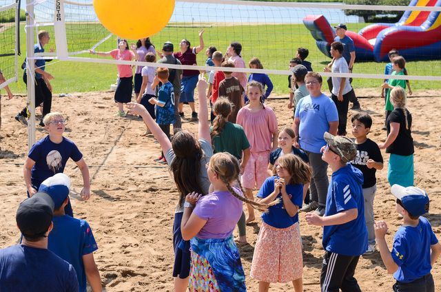 People playing beach volleyball on a sandy court.