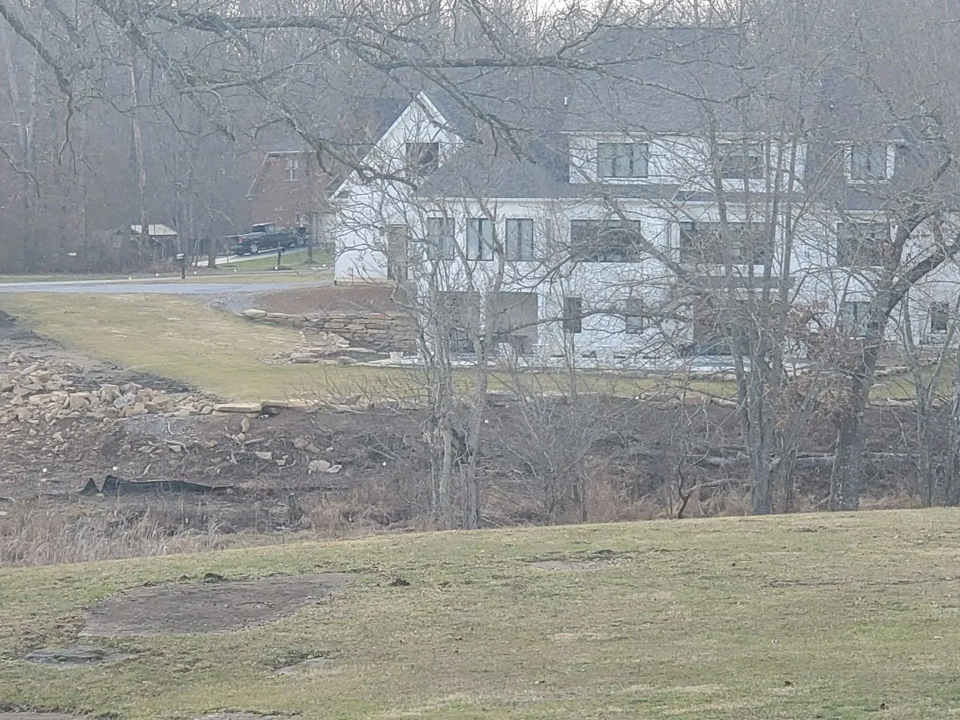 White house beside a leafless creek in a gray winter landscape