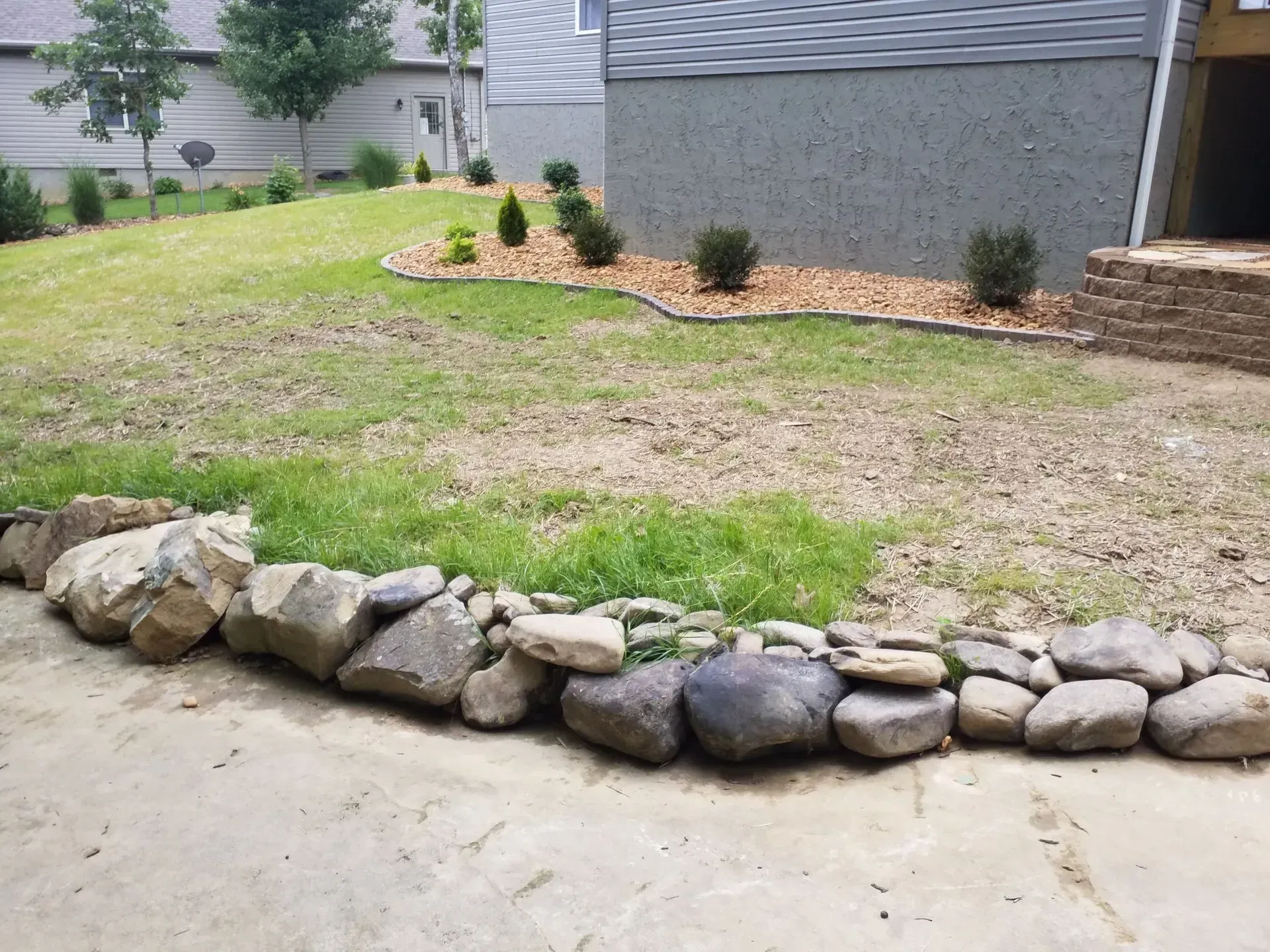 Rock border edging a small front yard mulch bed beside a house and driveway