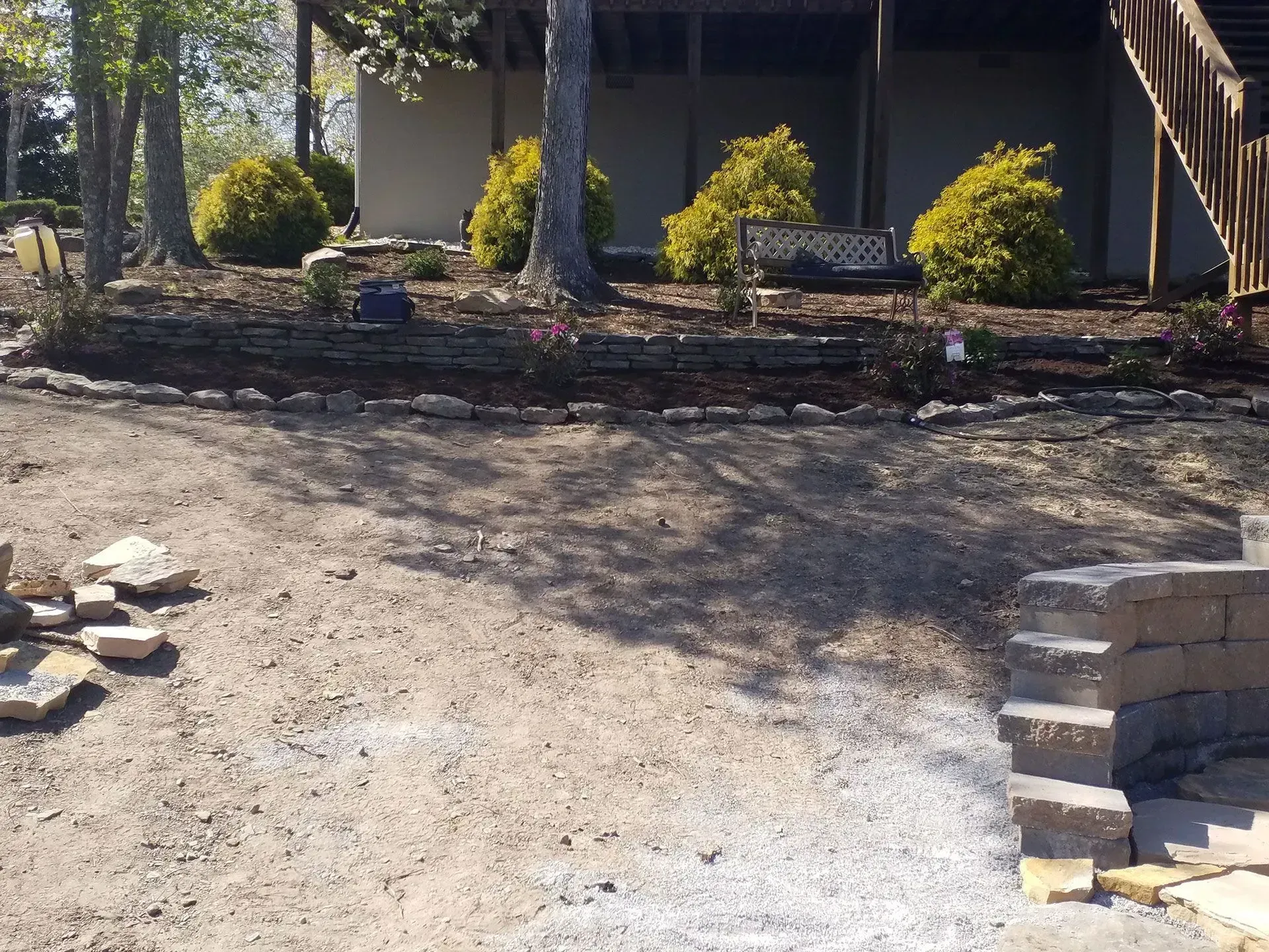 Gravel driveway under construction beside a house, with stone edging and landscaping in front.