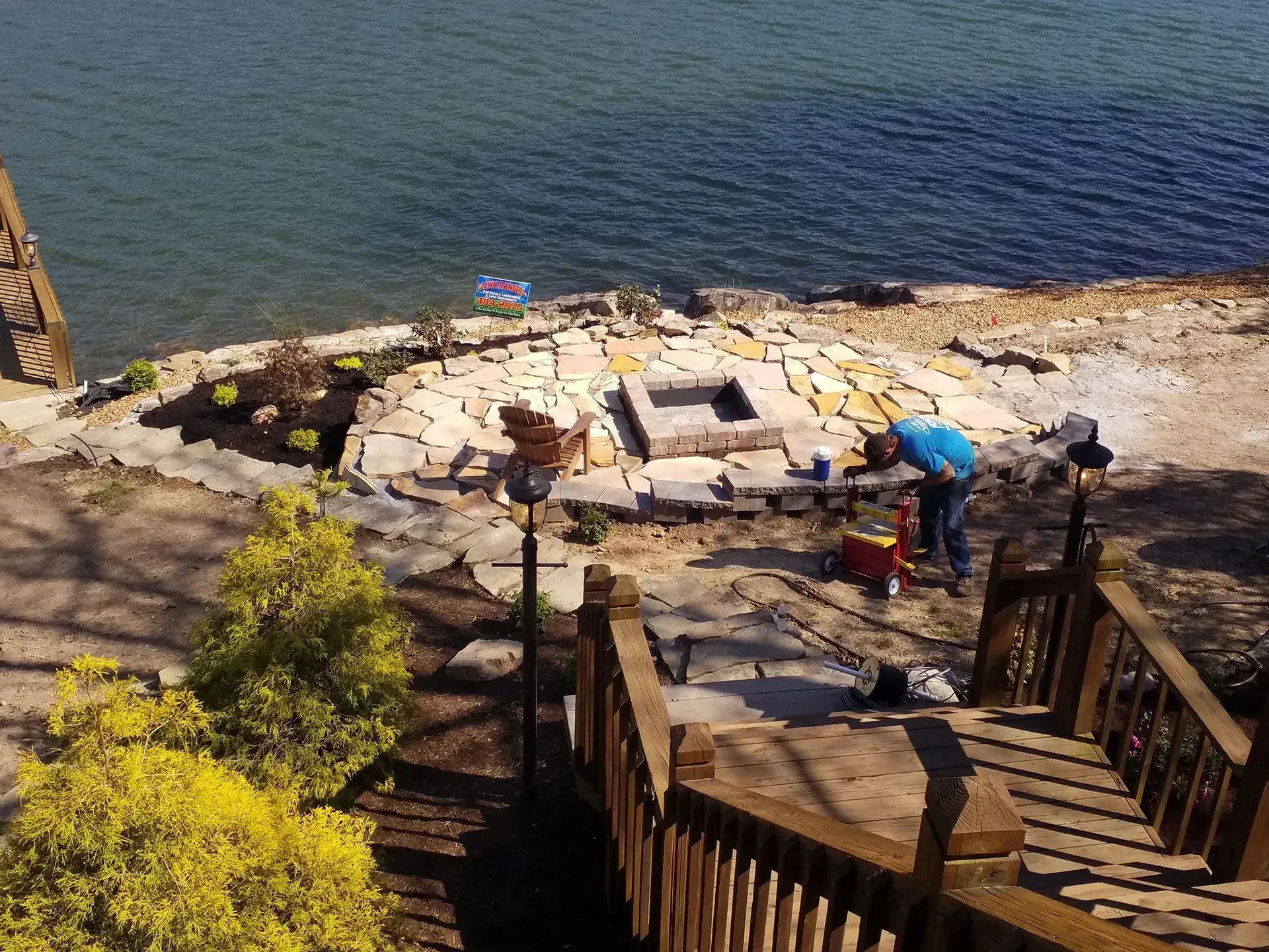 Seaside stone patio with umbrellas, loungers, and stairs descending to the water