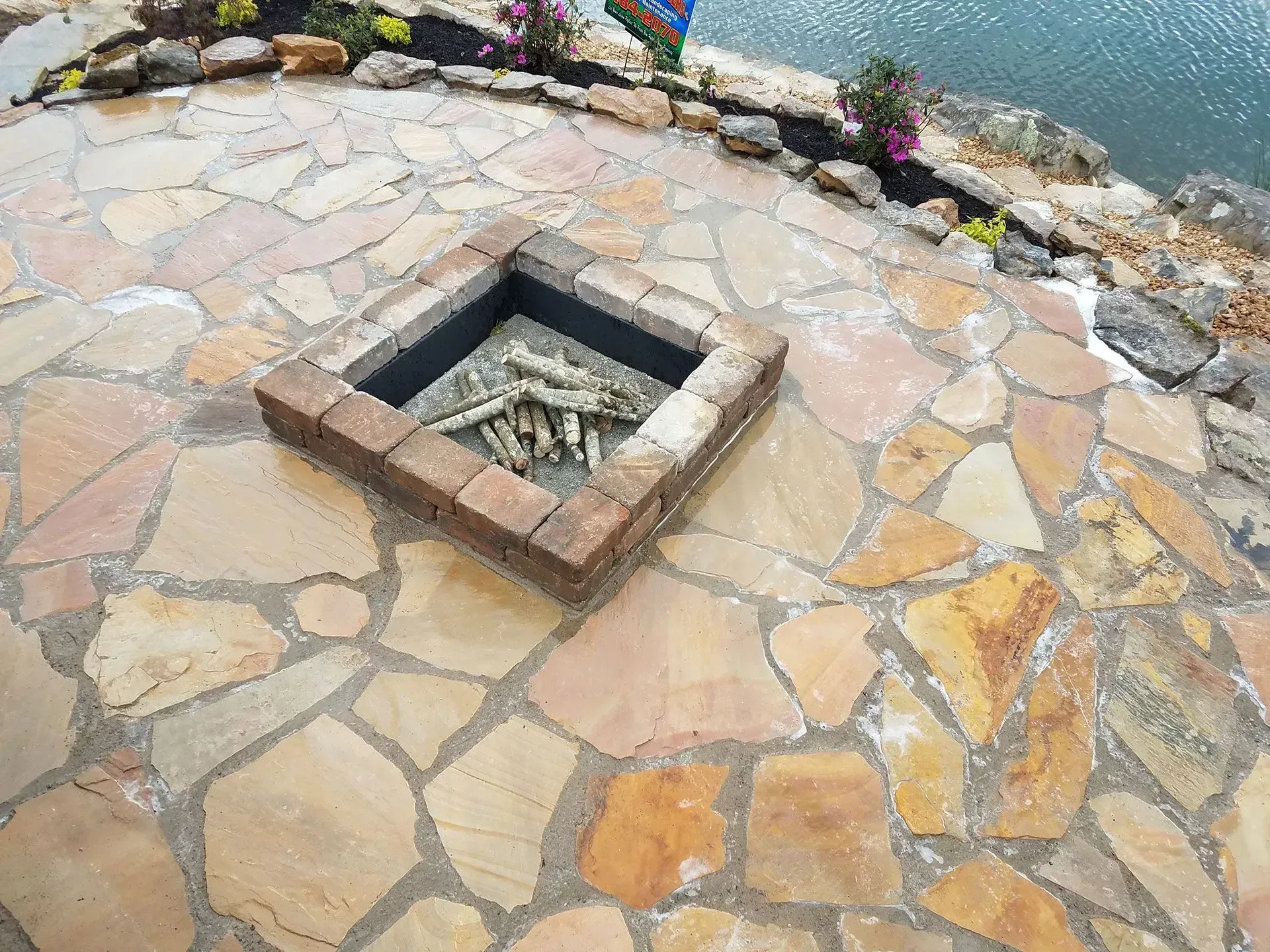 Stone patio with a square brick-framed fire pit in the center