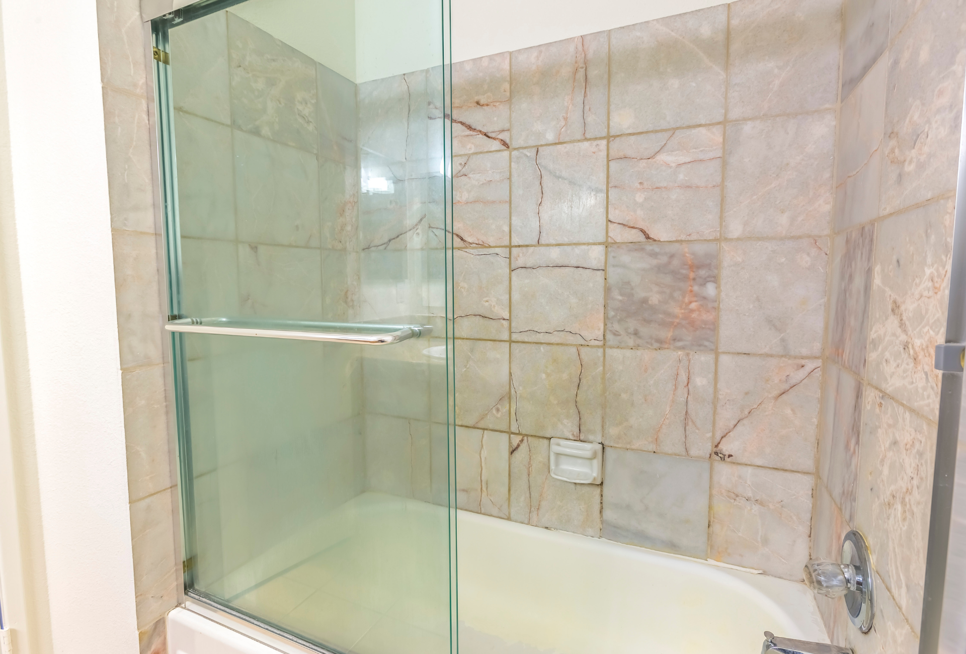 A bathroom with a walk in shower with a glass door.