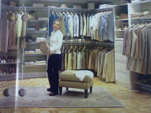 A woman is standing in a closet full of clothes