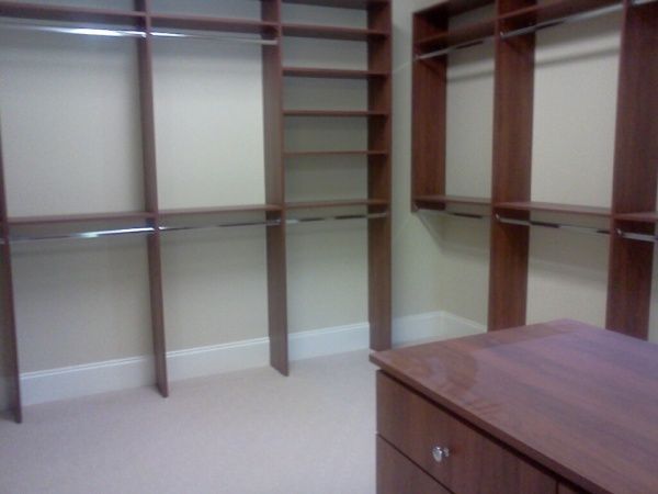 A walk in closet with lots of shelves and drawers