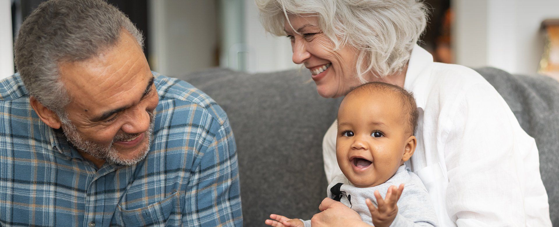A man and woman are sitting on a couch holding a baby.