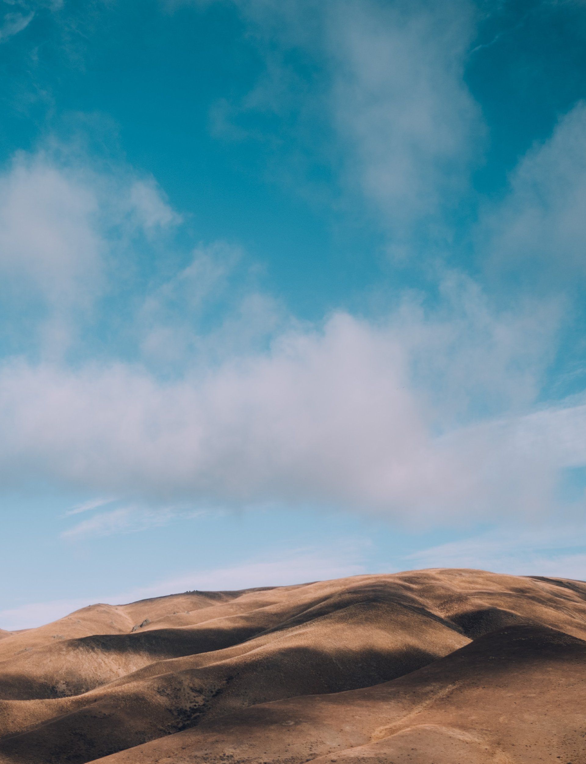 A desert landscape with a blue sky and clouds over the hills