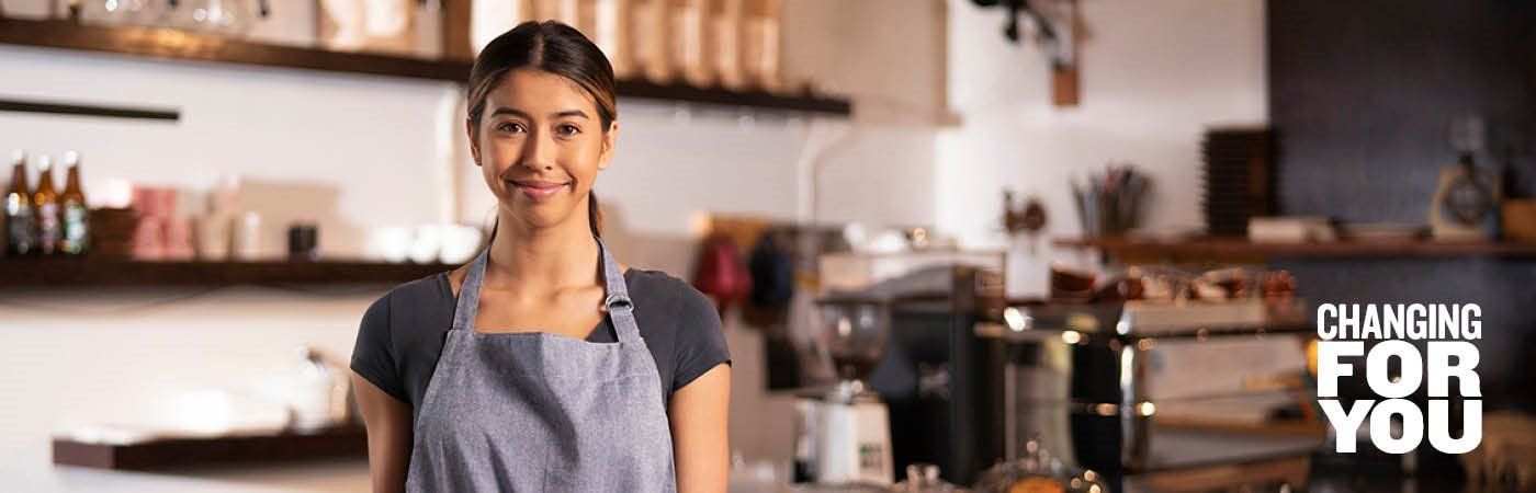 A woman in an apron is standing in a kitchen.